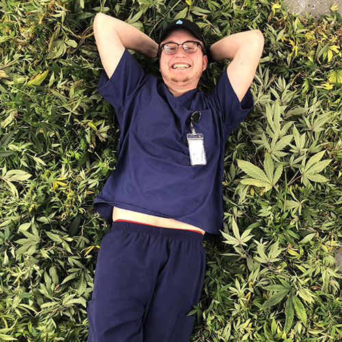 Riley Cepiel lays in a field of cannabis