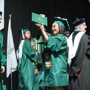 A grad holds up her diploma