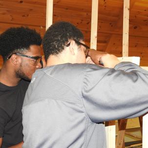 Two team members in Architectural Studies and Design program work together to build their design project at full-scale.