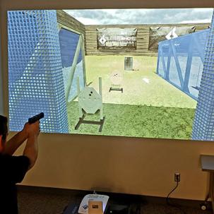 A Criminal Justice student uses the Laser Shot Law Enforcement Simulator.