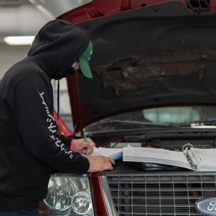 A student examines under the hood of a Ford vehicle.